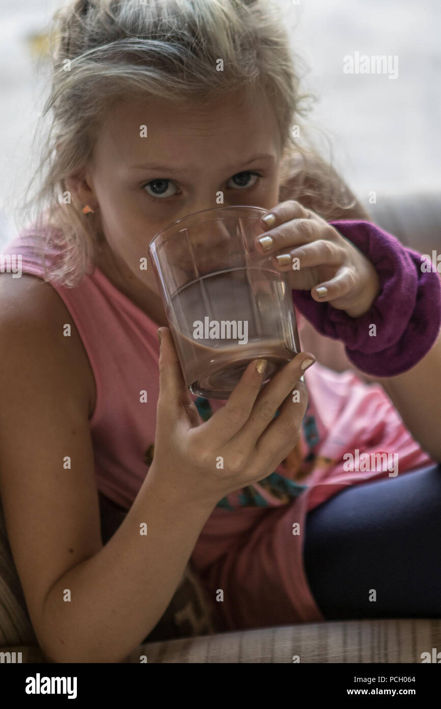 Blond 8 Jahr alt, Trinken chocalte Milch, bis zu Kamera schaut. Model Release #133 Stockfoto