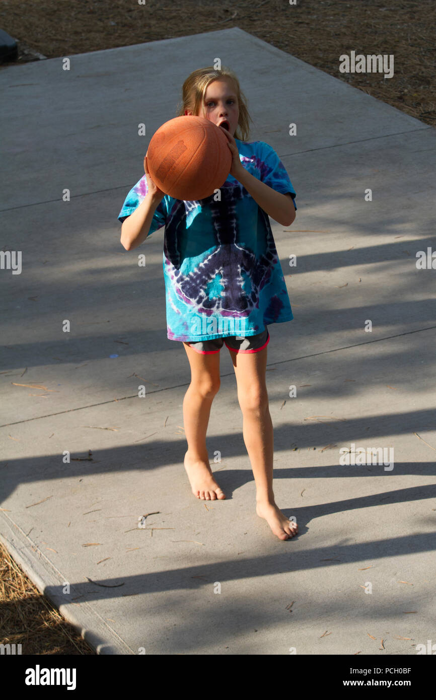 Hübsche 8-jährige Weiblich spielen Outdoor. Basketball, tragende T-Shirt und Shorts. Modell Relese #113 Stockfoto