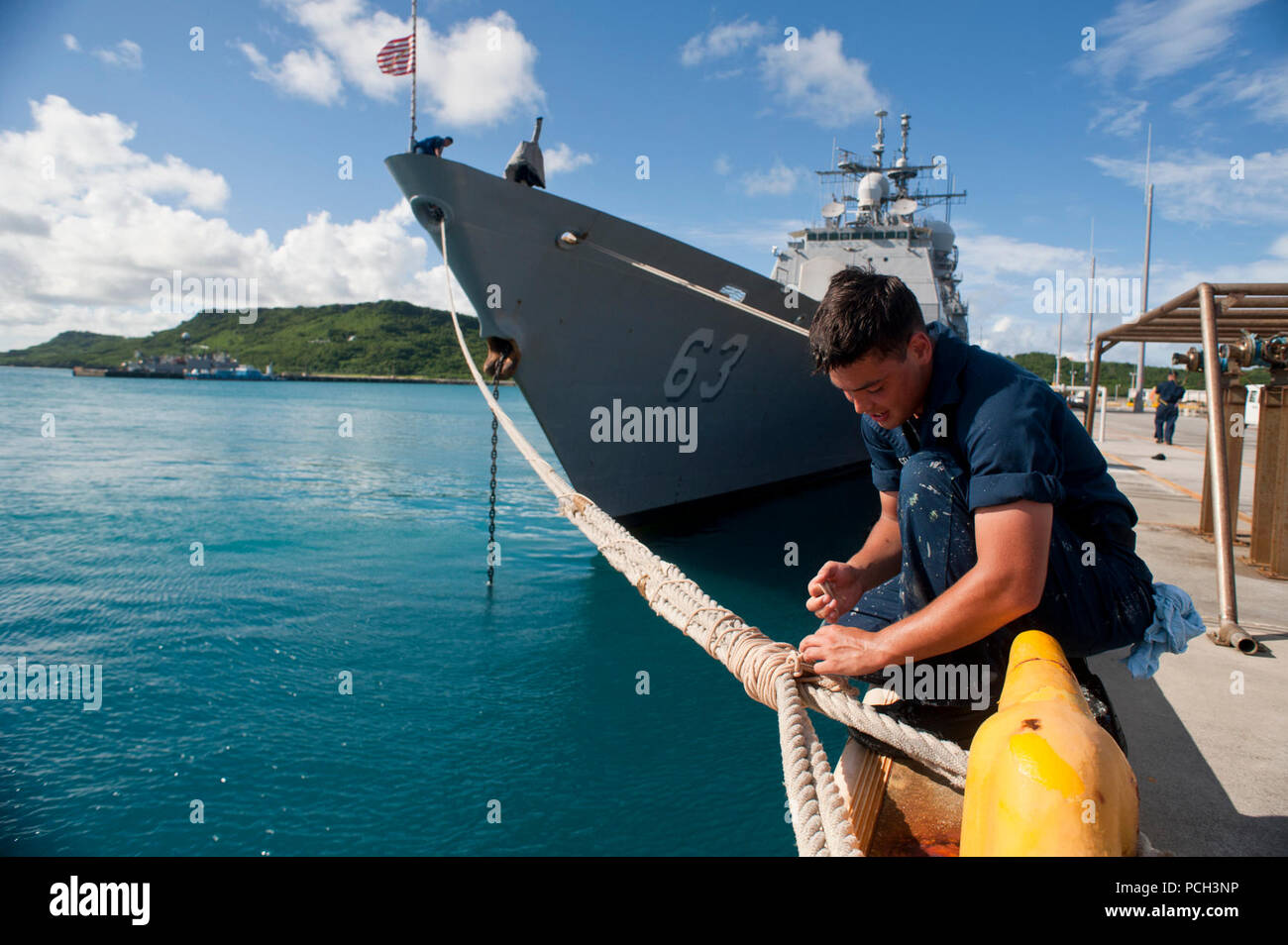 OKINAWA, Japan (Juli 23, 2012) Seaman Recruit James McGrath wickelt die Haltetaue der Ticonderoga-Klasse geführte-missile Cruiser USS Cowpens (CG63) kurz nachdem das Schiff vertäut Pier-Seite. Cowpens freut - Yokosuka, Japan eingesetzt und arbeitet in den USA 7 Flotte Verantwortungsbereich. Stockfoto