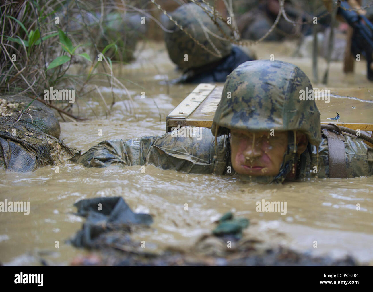 OKINAWA, Japan (Jan. 12, 2016), der Stern Frank S. Sysko zu Naval Mobile Konstruktion Bataillon (NMCB) 3 hält den Atem an, während er verlässt eine Schlamm gefüllten Graben während einer Jungle warfare training Evolution von Marines gehostet mit den Jungle Warfare Training Center (Jwtc). Die jwtc endurance Kurs Tests der Seabees, Ausdauer und die Fähigkeit, als Team zusammen zu arbeiten. NMCB3 ist in mehrere Länder im Pazifischen Raum von Operationen Durchführung von Bauleistungen und humanitäre Hilfe Projekte bereitgestellt. Stockfoto