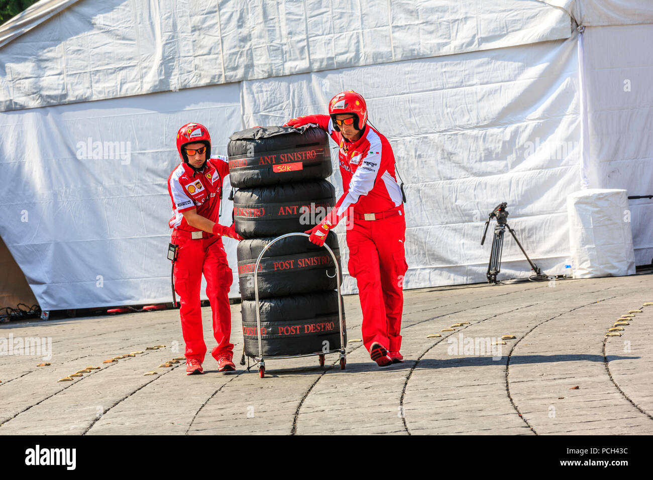 Mexiko City, Mexiko - 08 Juli, 2015: Pit Crew Transport einen Satz Felgen zum Boxenstopp für den Radwechsel Demonstration. Die Räder waren Verkehr auf seiner Abdeckung, die Abdeckung der Temperatur auf Sie pflegt und schützt Sie vor Schäden. Kommt mit der Legende "Ant Sinistro, Ant Destro Post Sinistro und Post Destro", das bedeutet "vorne links, vorne rechts, hinten links und hinten rechts" in Italienisch bzw., und mit einem Aufkleber mit der Beschriftung "AALGLATT" Das bedeutet, dass die Art der Reifen. Bei der Scuderia Ferrari Straße Demo von Telcel - ad infinitum. Stockfoto