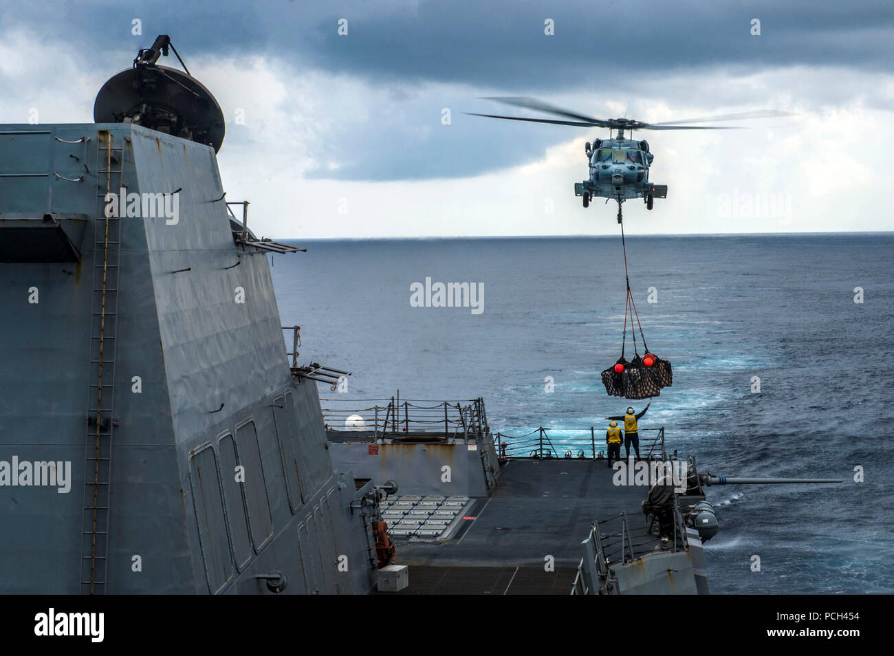 Ein U.S. Navy MH-60S Seahawk Helikopter Hubschrauber Meer Combat Squadron (HSC) 25 Anhang liefert die Lieferungen aus der Dry Cargo und Munition ship USNS Washington Kammern (T-AKE 11) (nicht abgebildet), die geführte Anti-raketen-Zerstörer USS Mustin (DDG89) während einer Auffüllung auf See im Südchinesischen Meer Okt. 20, 2014. Die mustin war auf Patrouille in den USA 7 Flotte der Verantwortung zur Unterstützung der regionalen Sicherheit und Stabilität in der Region. Stockfoto