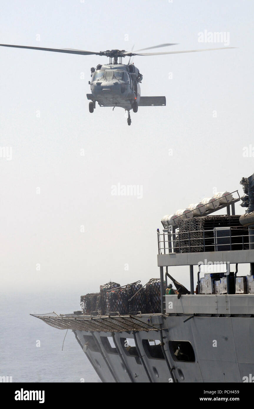 Ein U.S. Navy MH-60S Seahawk Hubschrauber, zugeordnet zu den Hubschrauber Meer Combat Squadron (HSC) 23, bereitet sich die Versorgung aus der militärischen Sealift Command schnell Combat support ship USNS Brücke (T-AOE 10) während einer vertikalen Auffüllung mit den Amphibischen dock Landung Schiff USS Comstock (LSD 45) im Persischen Golf Mai 17, 2011. Comstock ist unterwegs Unterstützung Maritime Security Operations und Theater Sicherheit Zusammenarbeit in den USA 5 Flotte Verantwortungsbereich. Stockfoto