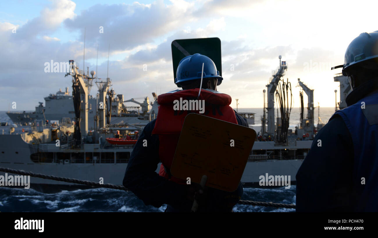 Ein US-Sailor, Mitte, an Bord des amphibious Transport dock Schiff USS Mesa Verde LPD (19) nutzt hand Paddles während einer Auffüll-anforderung auf See im Mittelmeer März 12, 2014 Mit einem nachfüllstation an Bord der Flotte Auffüllung öler USNS John Lenthall (T-AO 189) kommunizieren. Die Mesa Verde war Teil des Bataan amphibischen Bereitschaft Gruppe und war unterwegs in den USA 6 Flotte Verantwortungsbereich unterstützen Maritime Security Operations und Theater Sicherheit Bemühungen um Zusammenarbeit. Stockfoto