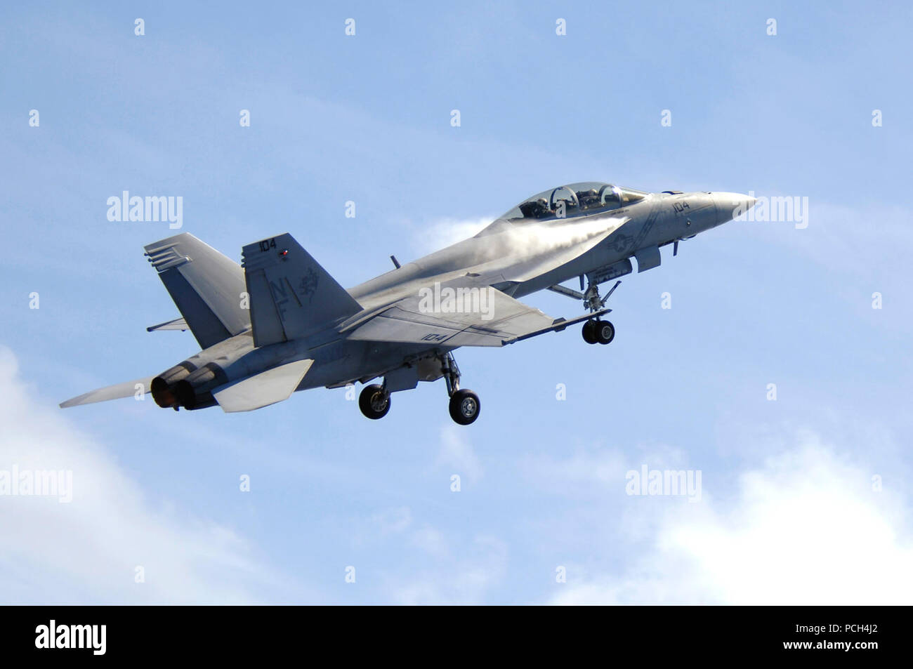 Wasserdampf strömt über die Flügel eines F/A-18F Super Hornet, Strike Fighter Squadron (VFA) 102 zugeordnet, da es sich um einen High-Speed-Pass, der während einer Air Power Demonstration über USS Kitty Hawk (CV 63). Kitty Hawk ist drei Monate in ihre Sommer Bereitstellung von Flotte Aktivitäten Yokosuka, Japan. Stockfoto