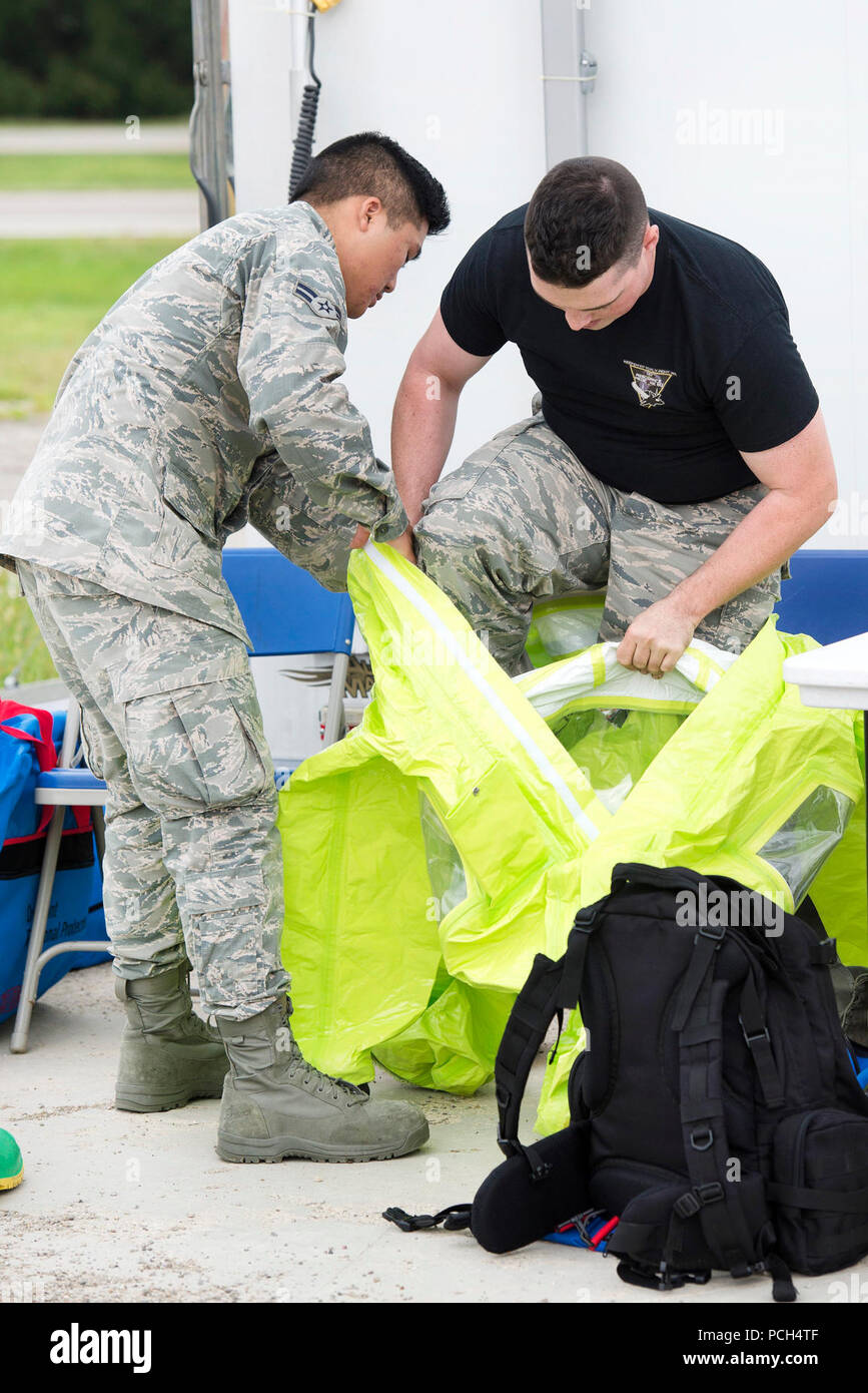 Airman 1st Class Matthew Streit, 88. Luft- und Raumfahrt Medizinische Squadron biologische Umwelttechnik Techniker, hilft, Co-worker Airman First Class Devon Rupert seinen schutzanzug vor der Annäherung an ein Auto mit einer unbekannten Pulver Substanz ist während einer Übung in Wright-Patterson Air Force Base, Ohio, Aug 4, 2017. Bereitschaft, Übungen werden routinemäßig Handgerät Zusammenhalt zu optimieren bei der Reaktion auf Notfälle. Stockfoto
