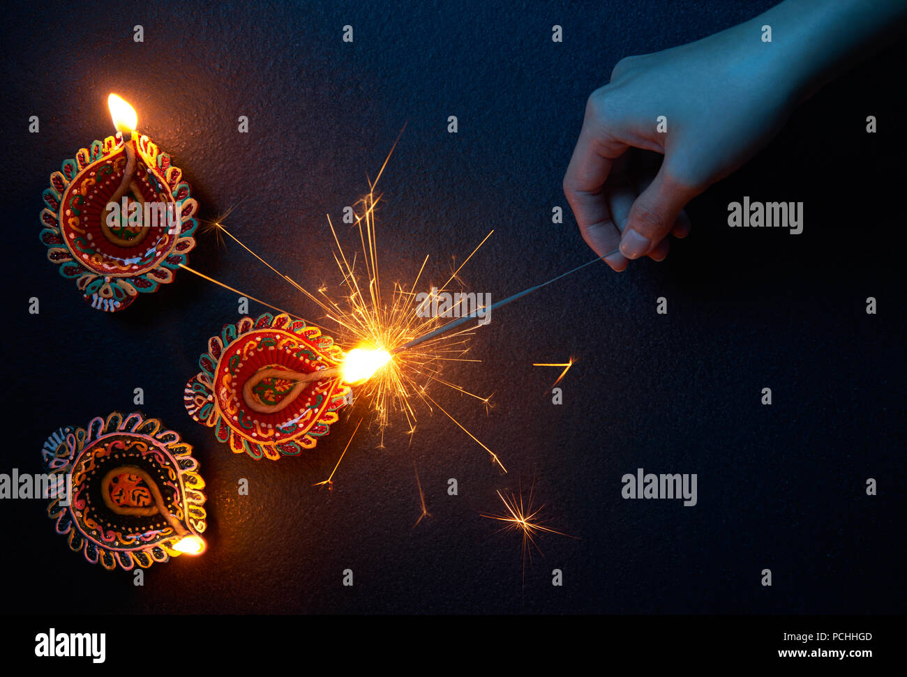 Beleuchtung eine Wunderkerze mit diya Lampe während Diwali Feier Stockfoto