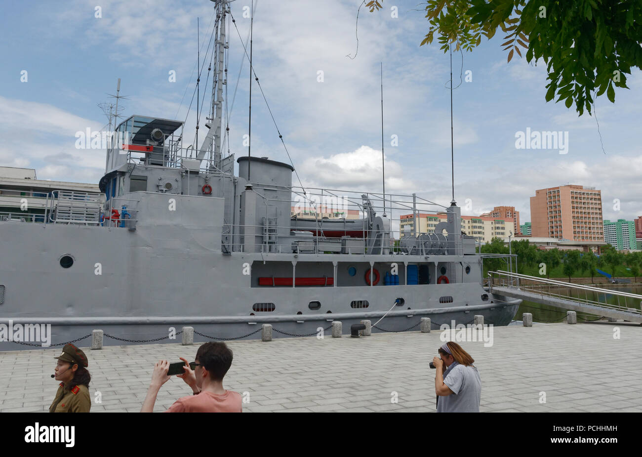 Touristen fotografieren und einen Guide an der USS Pueblo, der erfasst uns spy Schiff eine Ausstellung am siegreichen Krieg Museum, Pyongyang, Nordkorea Stockfoto