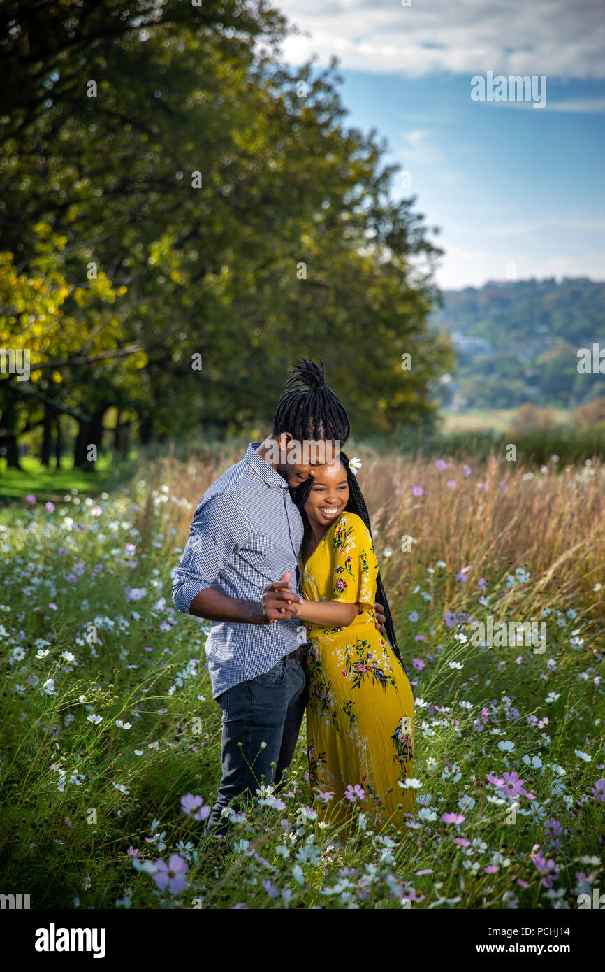 Paare, die in einem Feld von Blumen Stockfoto