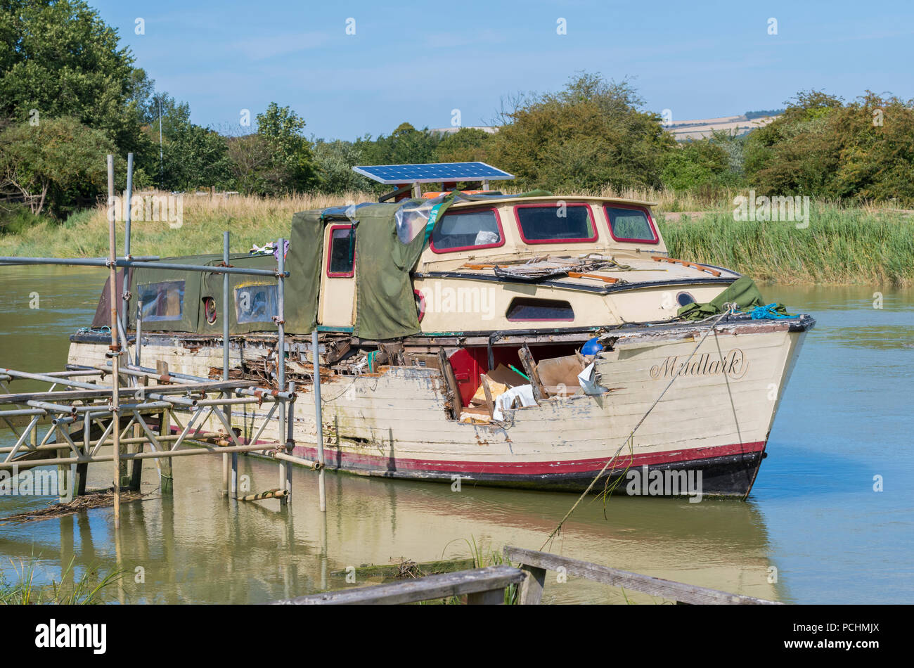 Alten hölzernen Boot vernachlässigt mit Bohrung und verrottendes Holz auf einem Ponton auf dem Fluss Arun in Arundel, West Sussex, England, UK. Stockfoto
