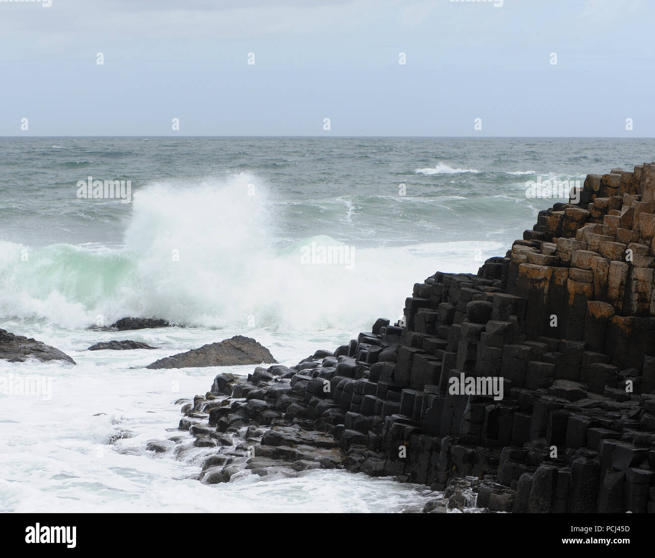 Wellen brechen im vieleckigen Basaltsäulen Giant's Causeway. Bushmills, County Antrim, Nordirland, Großbritannien. Stockfoto