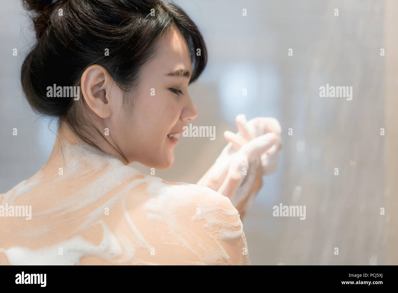 Junge asiatische Frau unter der Dusche im Badezimmer mit Dusche. Suchen glücklich und entspannen. Stockfoto