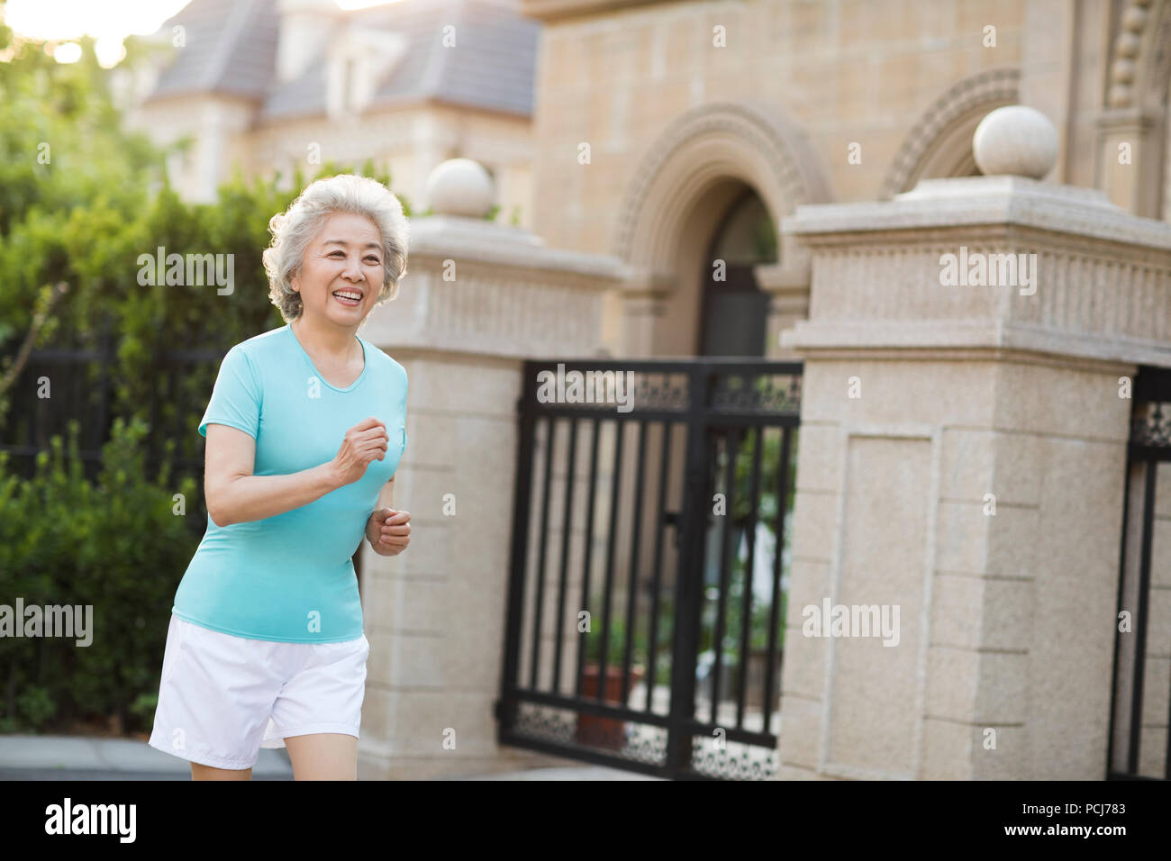 Freundliche ältere chinesische Frau joggen außerhalb Stockfoto