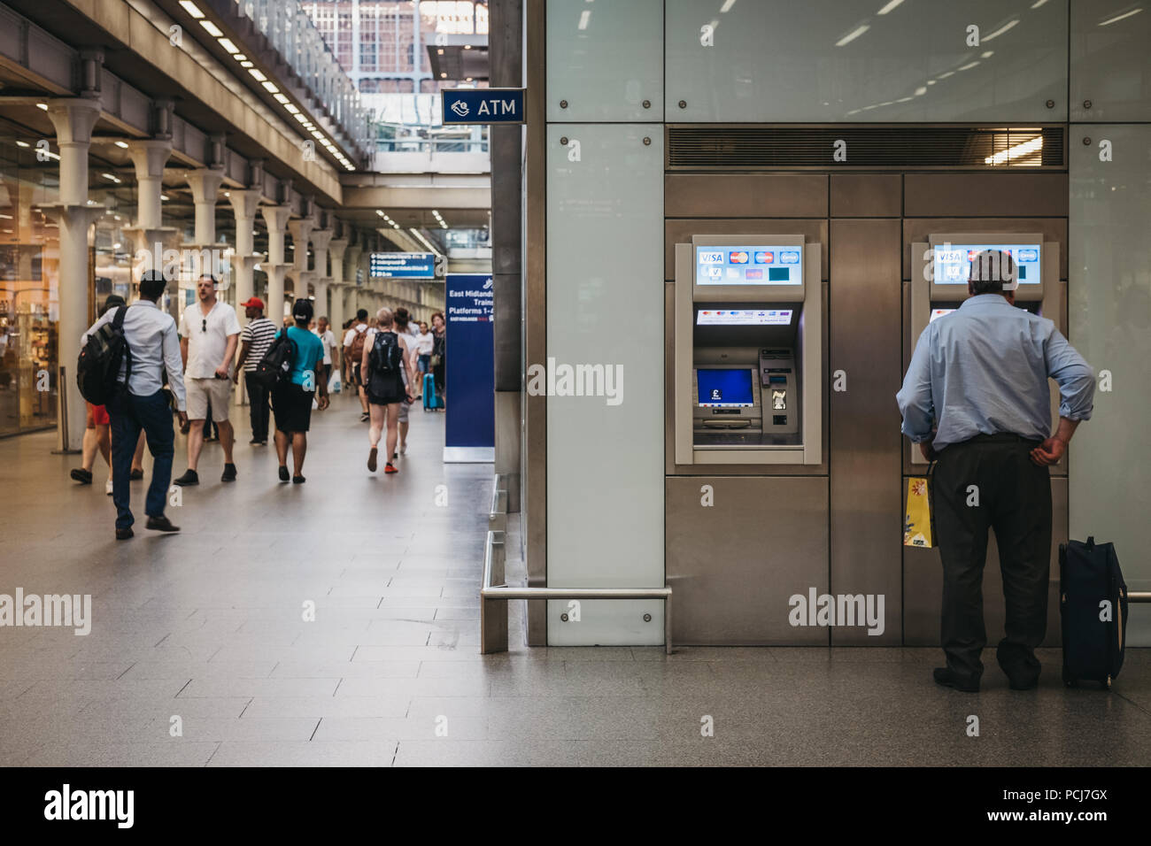 Mann mit einem Geldautomaten in Bahnhof St. Pancras, London, UK, Menschen vorbei gehen. Stockfoto