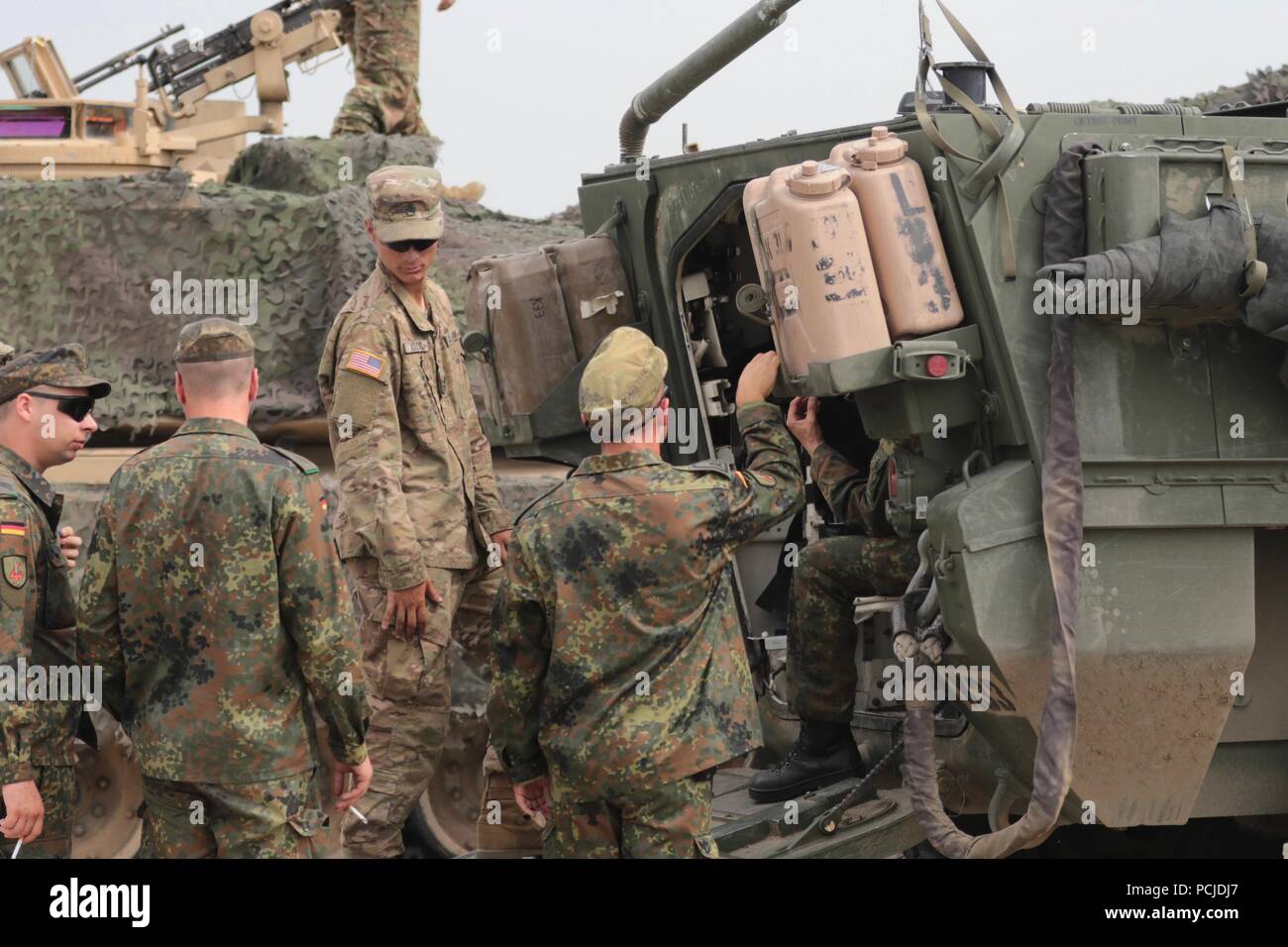 Staff Sgt. Keenan M. Kozak, einem Tank Commander mit dem Fort Hood auf der Grundlage Charlie Company, 2 Squadron, 5th Cavalry Regiment, hört zu Fragen von deutschen Soldaten über die Stryker Fahrzeug vor der Eröffnungsfeier von edlen Partner 18 am Wasiani, Georgien am 1. August 2018. Die US-Armee Europa übung Georgisch, regionale Partner und US-Streitkräfte Bereitschaft und Interoperabilität in eine realistische und anspruchsvolle multinationalen Umfeld verbessern. U.S. Army National Guard Foto: Staff Sgt. R.J. Lannom Jr Stockfoto