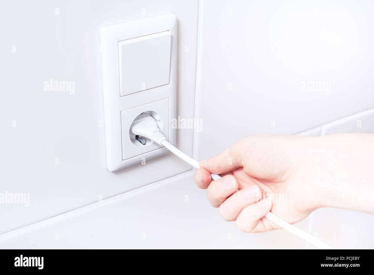 Ziehen Sie ein elektrisches Kabel aus der Steckdose Energie sparen Stockfoto