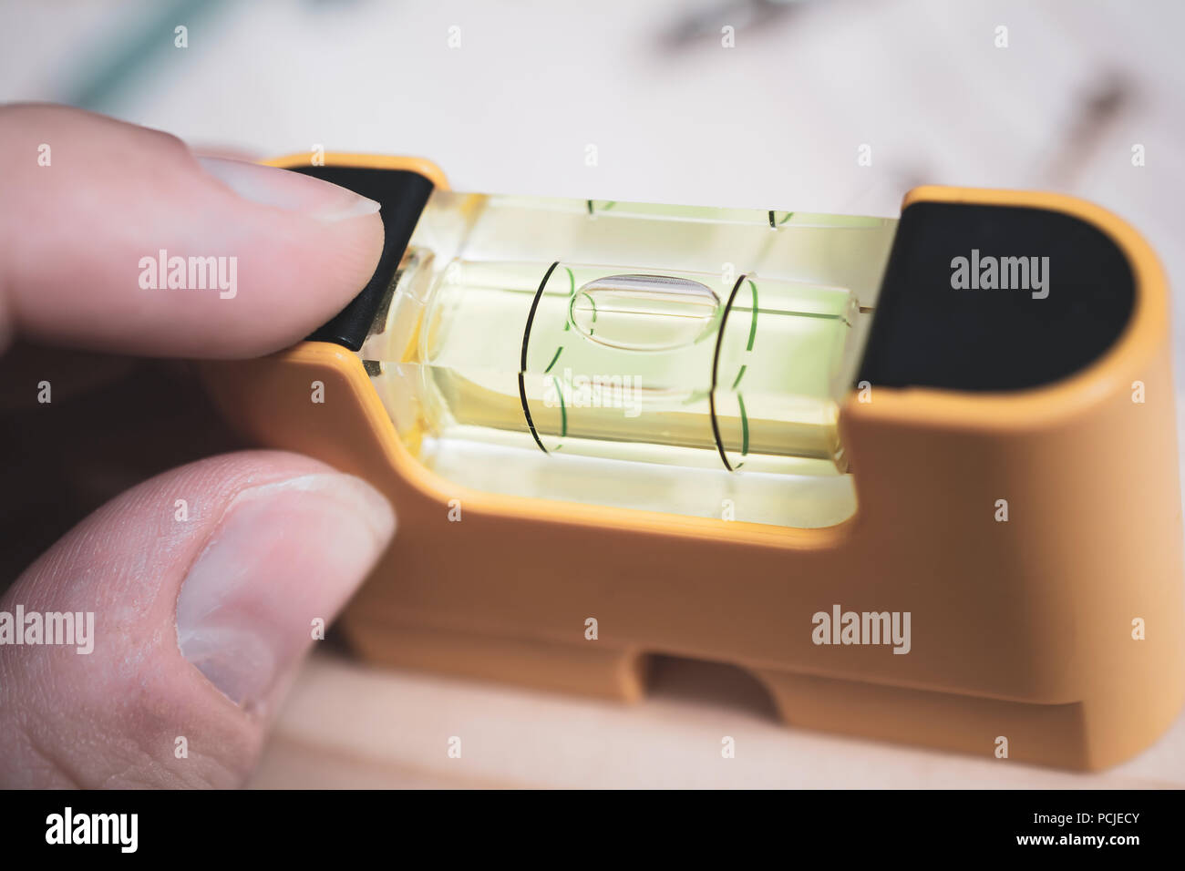 Männliche Finger halten einen kleinen gelben Wasserwaage, um zu prüfen, ob die Blase in der Mitte, DIY Home Improvement Konzept ist Stockfoto