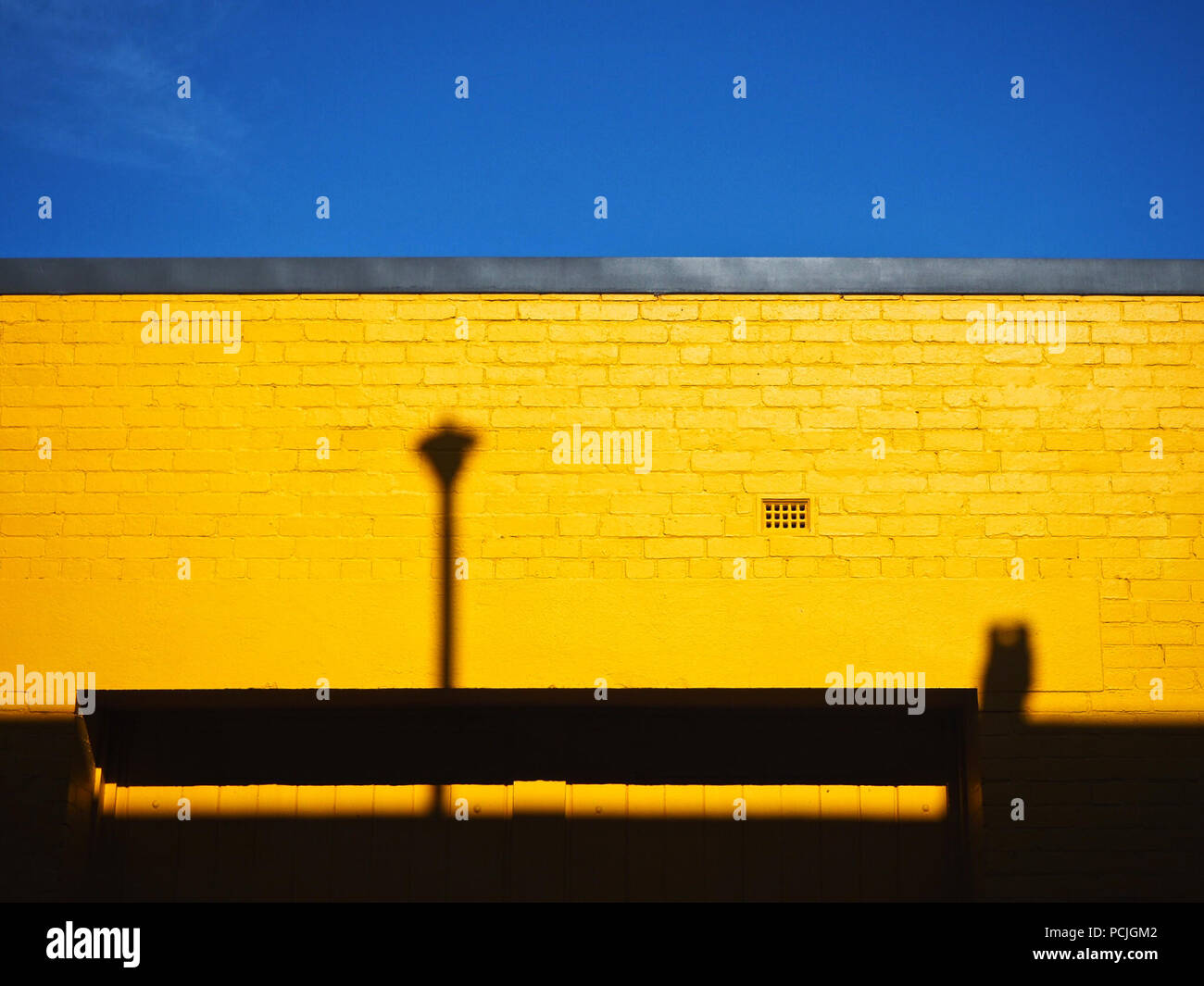 Gelbe Wand mit Schatten vor blauem Himmel, Australien Stockfoto