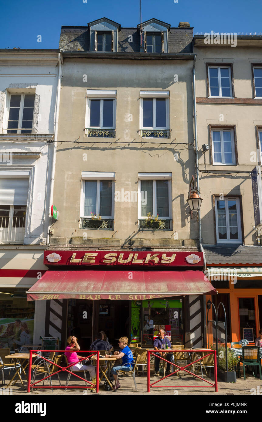 Zwei Personen an einem Tisch sitzen in der Sonne außerhalb der Le Sulky Cafe in der High Street von Cormeilles, Normandie, Frankreich Stockfoto