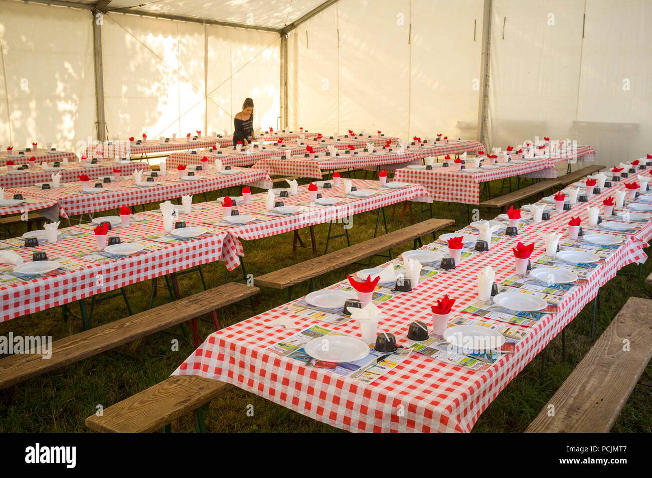 Eine Kellnerin bereitet die Tabellen für das Dorf Essen in St. Pierre de Cormeilles mit Tischen mit rot-weiß karierten Tischdecken festgelegt Stockfoto