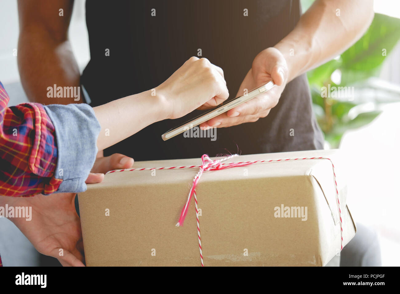 Frau anhängen Signatur unterschreiben auf dem Smartphone nach Kartons von Delivery Man shopping erhalten Stockfoto