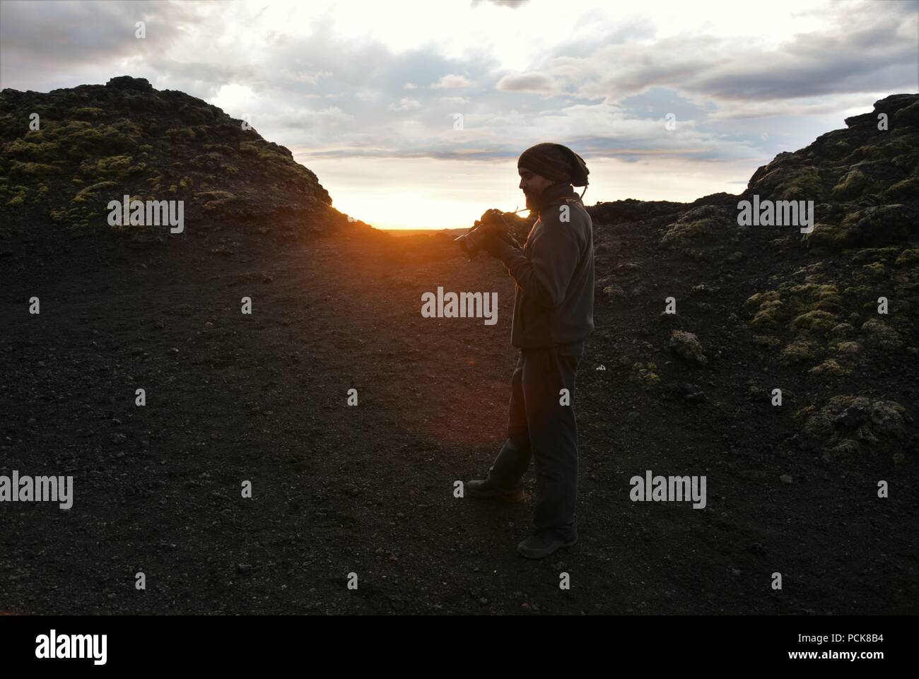 Eine abenteuerliche Fotograf klettert Krafla Vulkan und Fotos von lava Ruinen im Sonnenuntergang Stockfoto