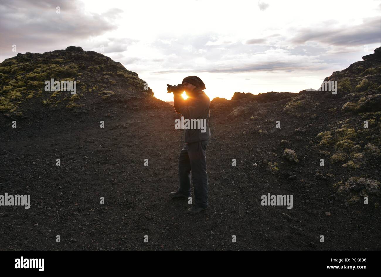 Eine abenteuerliche Fotograf klettert Krafla Vulkan und Fotos von lava Ruinen im Sonnenuntergang Stockfoto