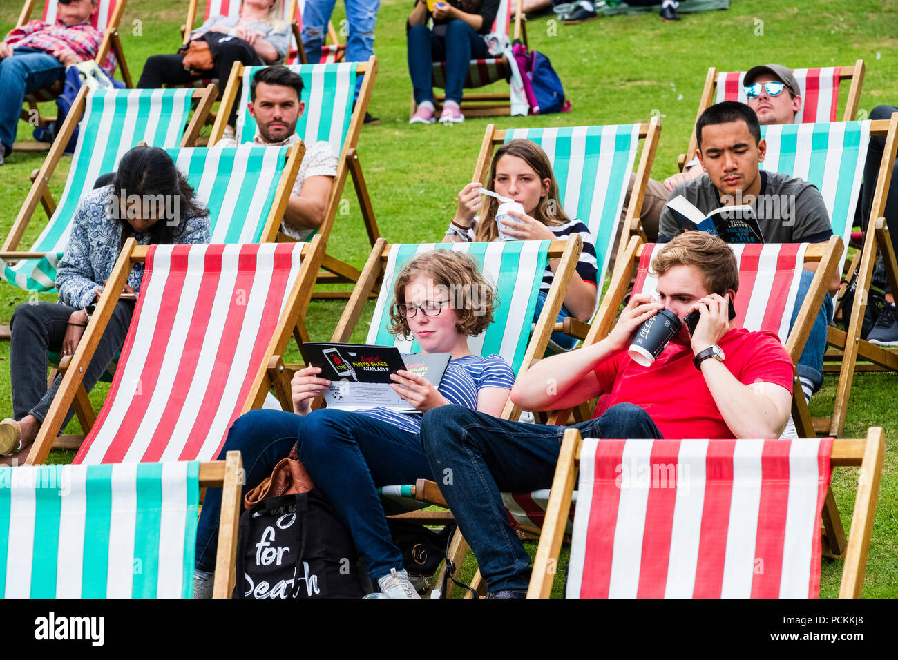 Die Menschen auf den Liegestühlen im Princes Street Gardens in Edinburgh an einem warmen Sommernachmittag. Schottland, Großbritannien Stockfoto