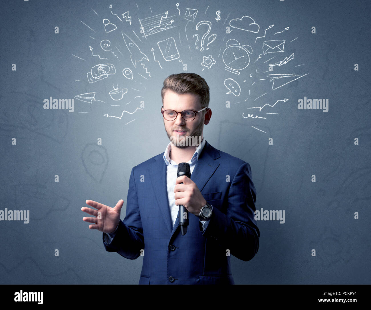 Geschäftsmann sprechen in das Mikrofon mit gemischten Doodles über seinem Kopf Stockfoto