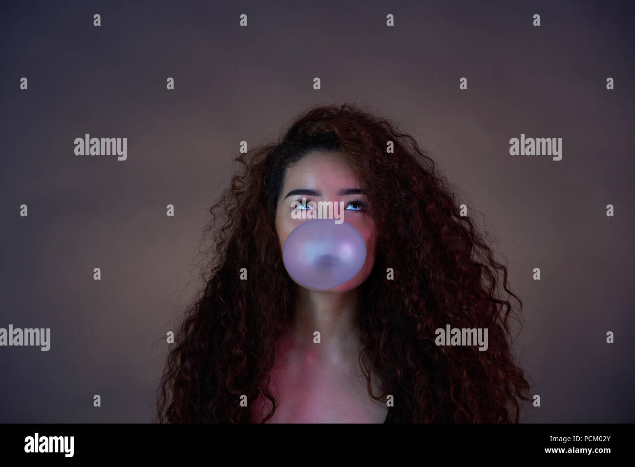 Blasen Bubble Gum ball Thema. Portrait von Teenager mit Blasen gummi ball auf braunem Hintergrund Stockfoto