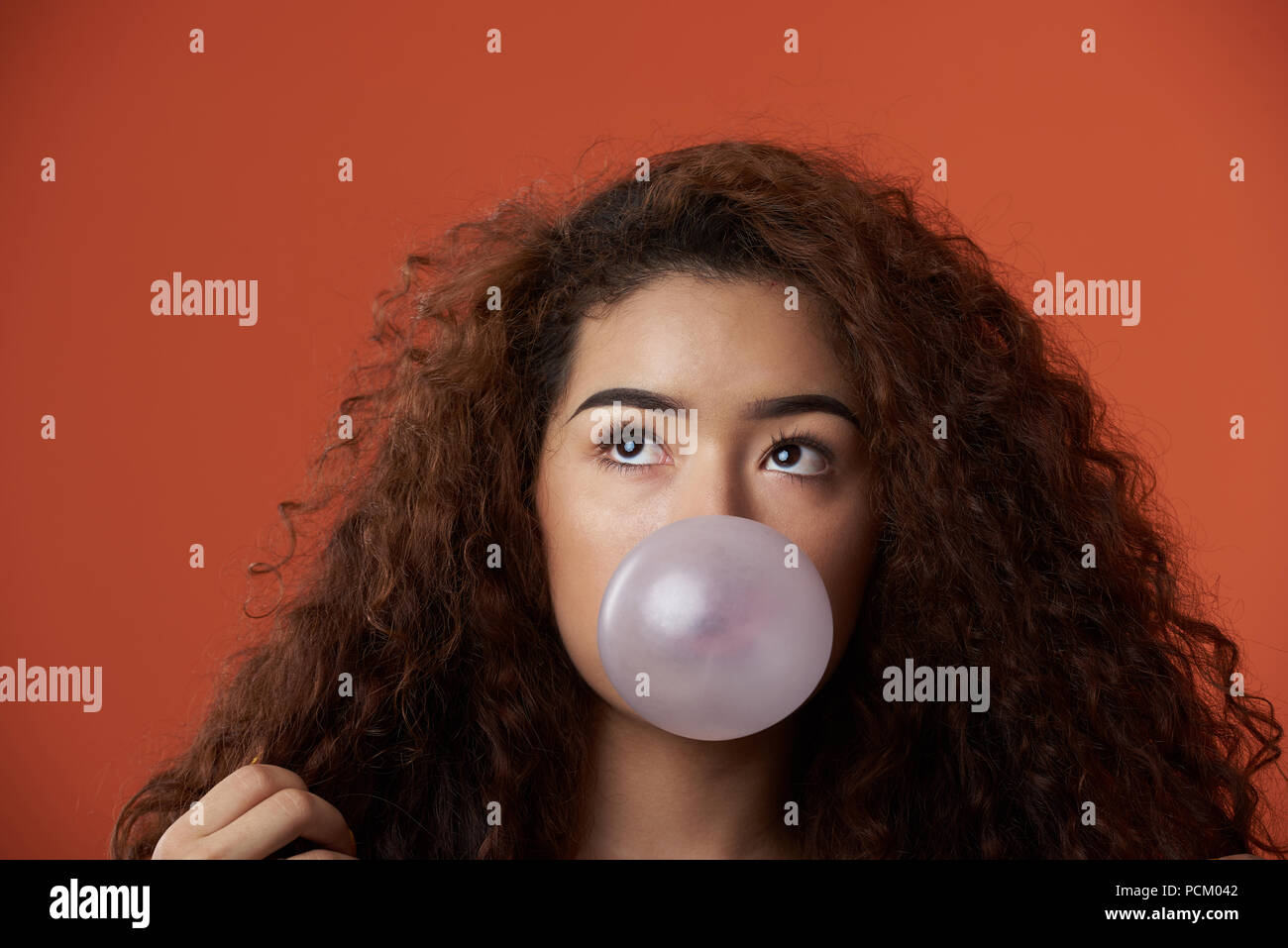 Portrait von jugendlichen Mädchen mit Bubble gum Ball in Orange Studio Hintergrund Stockfoto
