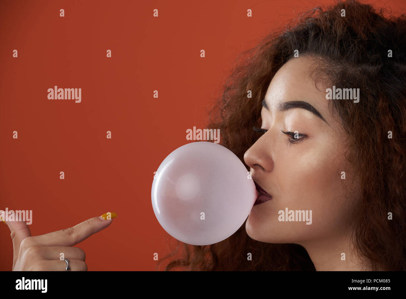 Junge Frau schlag Bubble Gum schlag Portrait auf orange Farbe Hintergrund isoliert Stockfoto