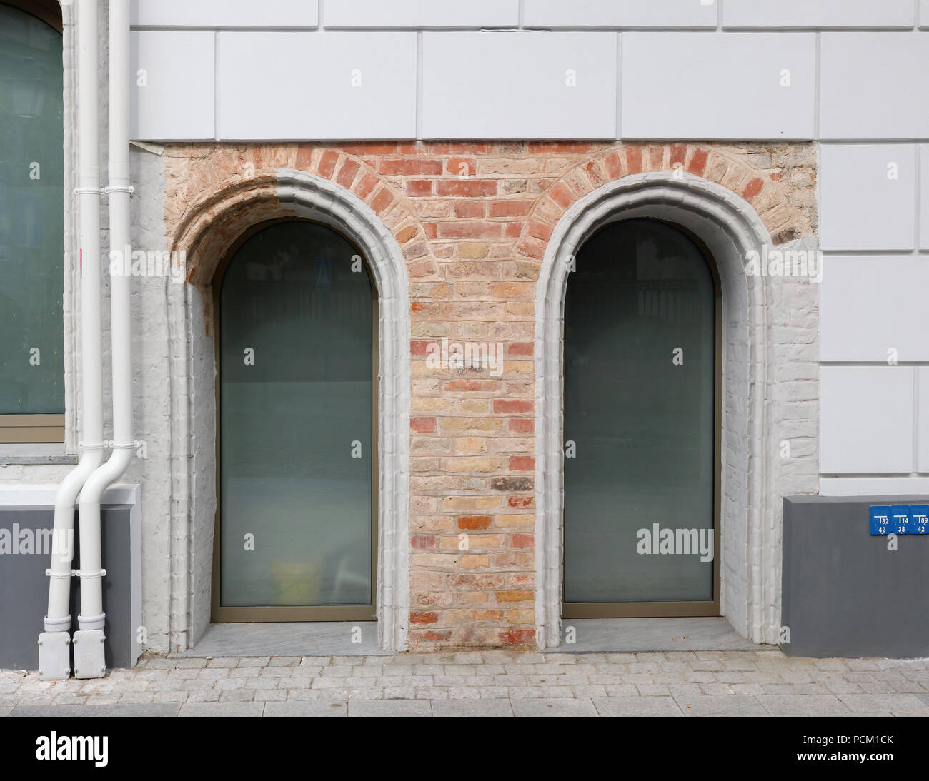 Zwei Kunststoff Rundbogenfenster in einem roten Ziegelmauer eines alten restaurierten Haus Stockfoto