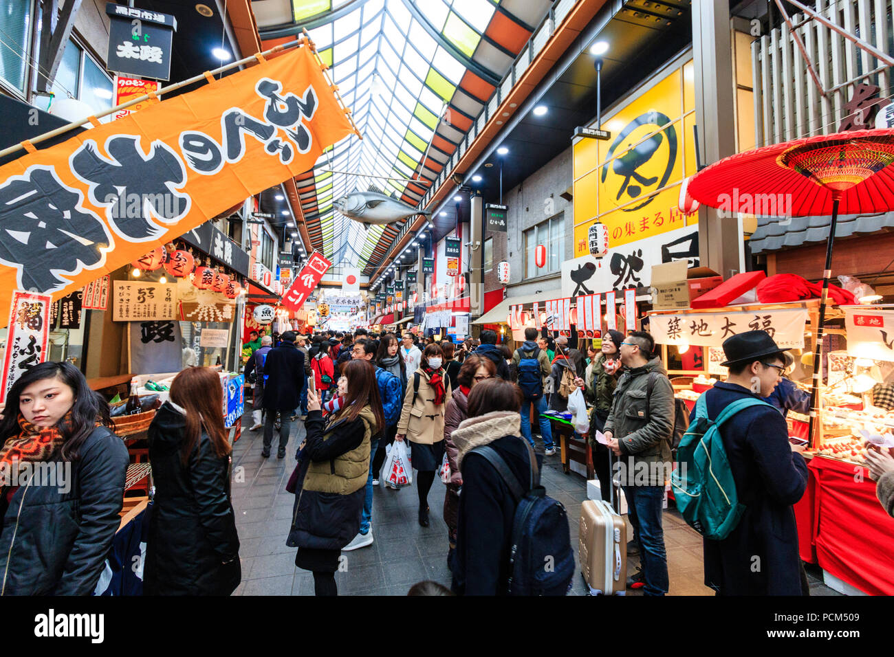 : Kuromon Ichiba, Küche essen Osaka's Markt. Blick entlang Arcade mit verschiedenen Ständen und Geschäften auf beiden Seiten der Arcade. Besetzt mit Menschen überfüllt. Winte Stockfoto