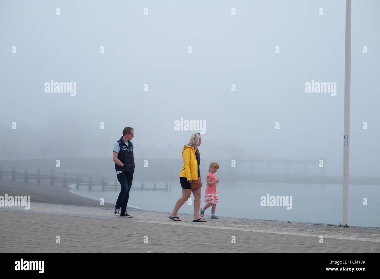 Aberystwyth Wales UK, Freitag, 03. August 2018 Großbritannien Wetter: Menschen zu Fuß entlang der Promenade Aberystwyth an einem kühlen und nebligen Abend so viel der Süden und Osten des britischen Erfahrungen rekordverdächtige hohe Temperaturen Foto © Keith Morris/Alamy leben Nachrichten Stockfoto