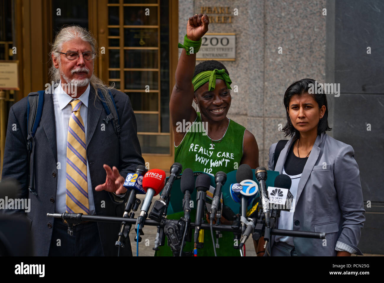 New York, New York, USA, 3. August 2018 Einwanderung Aktivist Therese Patricia Okoumou, mit Rechtsanwälten an Ihrer Seite, spricht vor Bundesgericht in Manhattan nach Anhörung zu übertreten und ordnungswidriges Verhalten. Okoumou skaliert der Sockel der Freiheitsstatue am 4. Juli 2018, gegen Trump administration Einwanderungspolitik zu protestieren. Okoumou trug ein grünes Kleid vor Gericht mit den Worten "Ich interessiere mich dafür, warum nicht du?" - eine Antwort auf die erste Dame Melania Trump, der eine Jacke mit den Worten "Ich trug wirklich egal, u tun?" Wenn Sie eine Einrichtung für Kinder mit Migrationshintergrund im Juni besuchte. Stockfoto