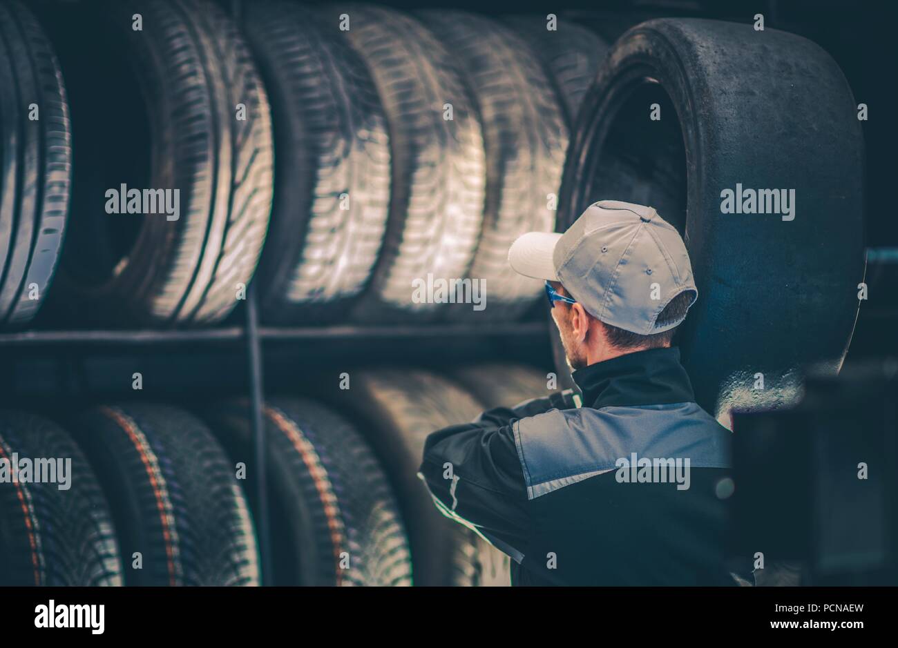 Auto Reifen Service Arbeitnehmer Bewegen gebrauchte Reifen Rund um den Shop. Stockfoto