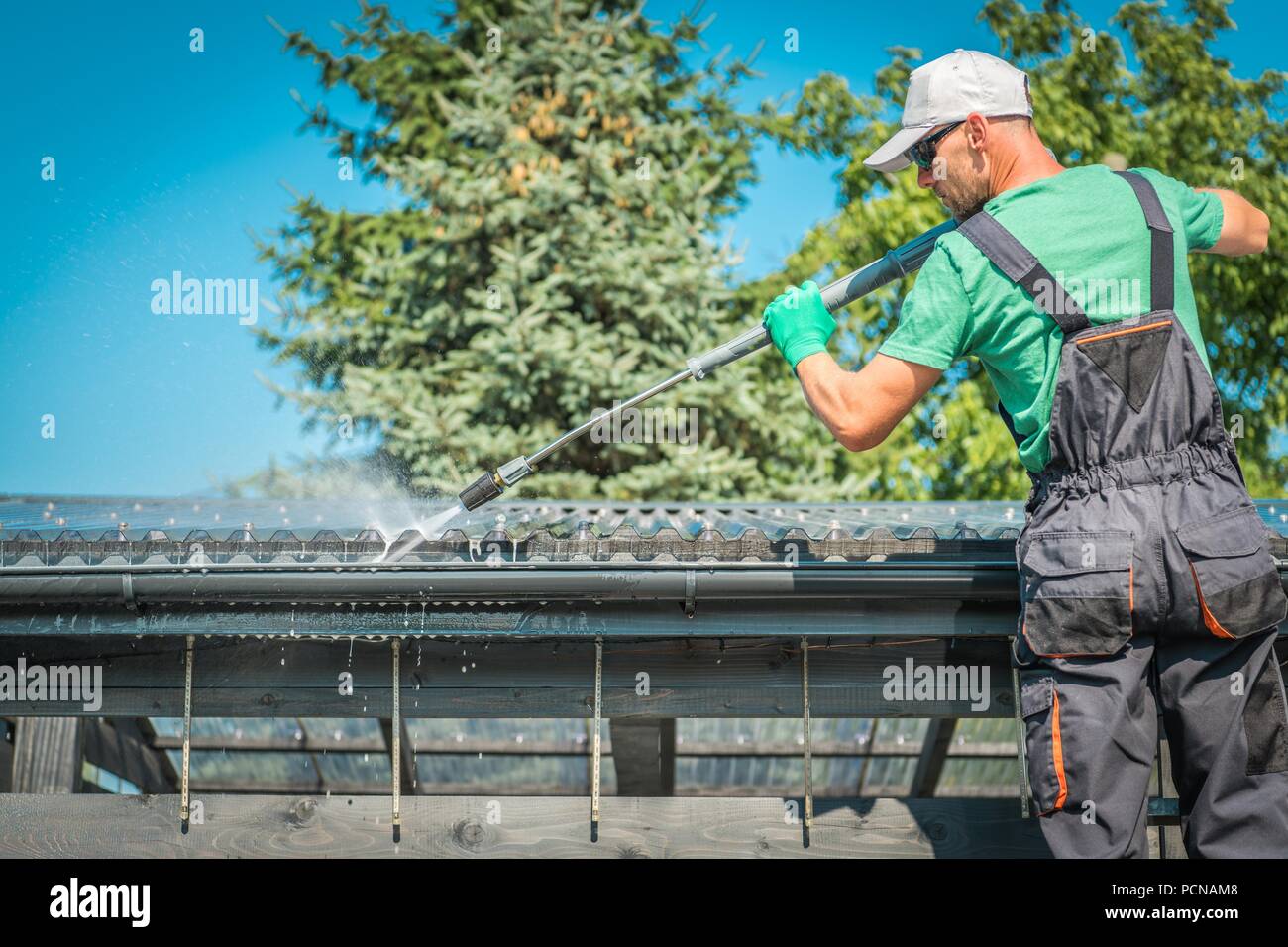 Dach und Dachrinnen Power Reinigung mit Hochdruckreiniger. Kaukasische Arbeiter. Stockfoto