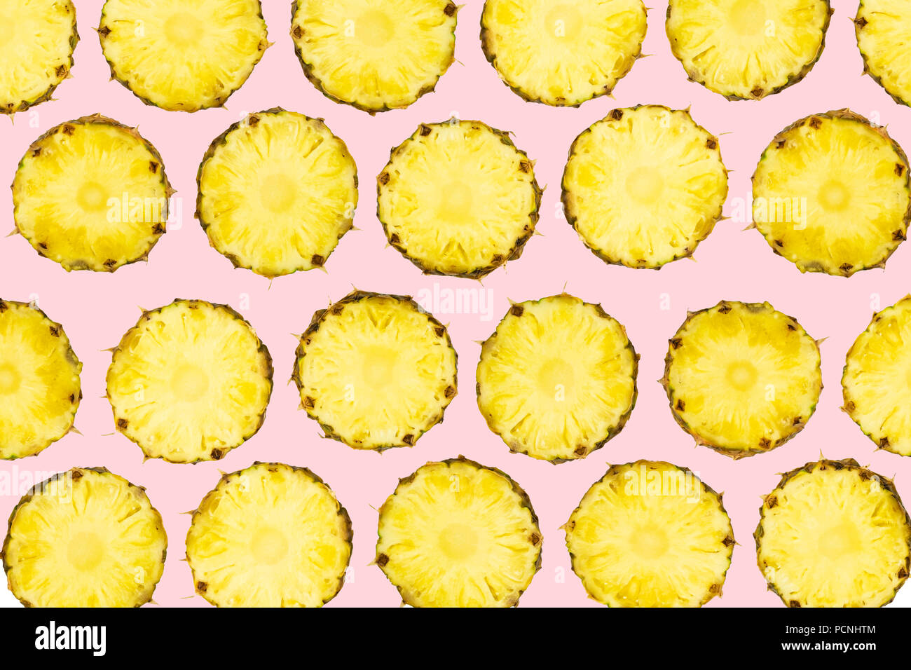 In Scheiben geschnittene Ananasstücke lag in Muster auf isolierte leicht rosa unterlegt. Muster der frisch geschnittene Ananas Obst auf lebhaften Hintergrund. Stockfoto