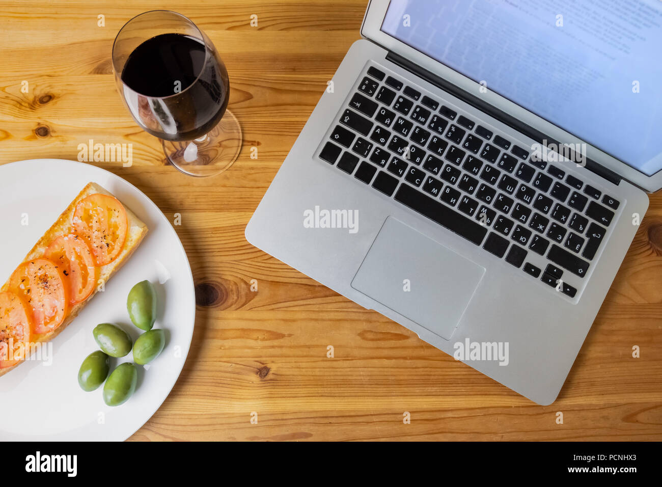 Blick von oben auf die Laptop und Licht am Abend Brot, Oliven und Wein. Flach Konzept der Abendessen und Laptop Kombination von natürlichen Holz Hintergrund Stockfoto