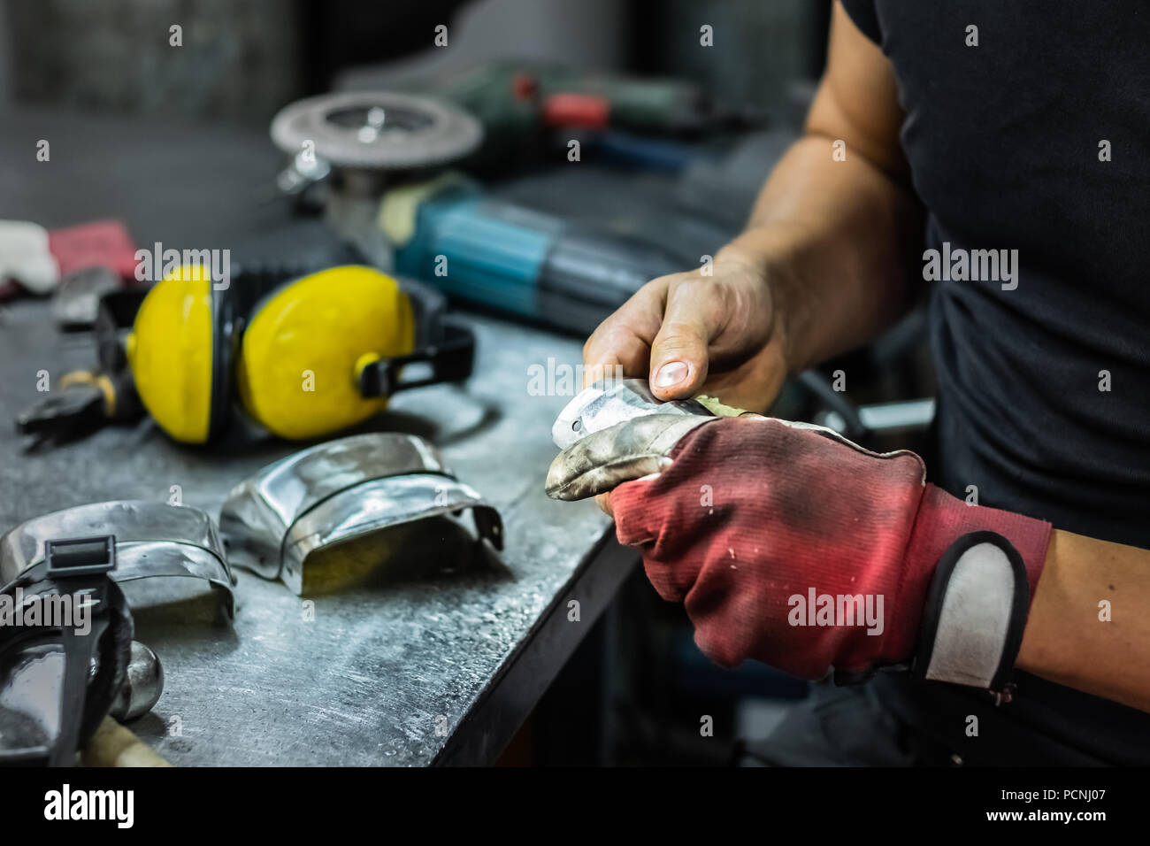Männliche Metallbauer Montage Stück der mittelalterlichen Rüstung. Man Hände Behandeln von Metallen Teile der Hardware in einem Workshop Stockfoto