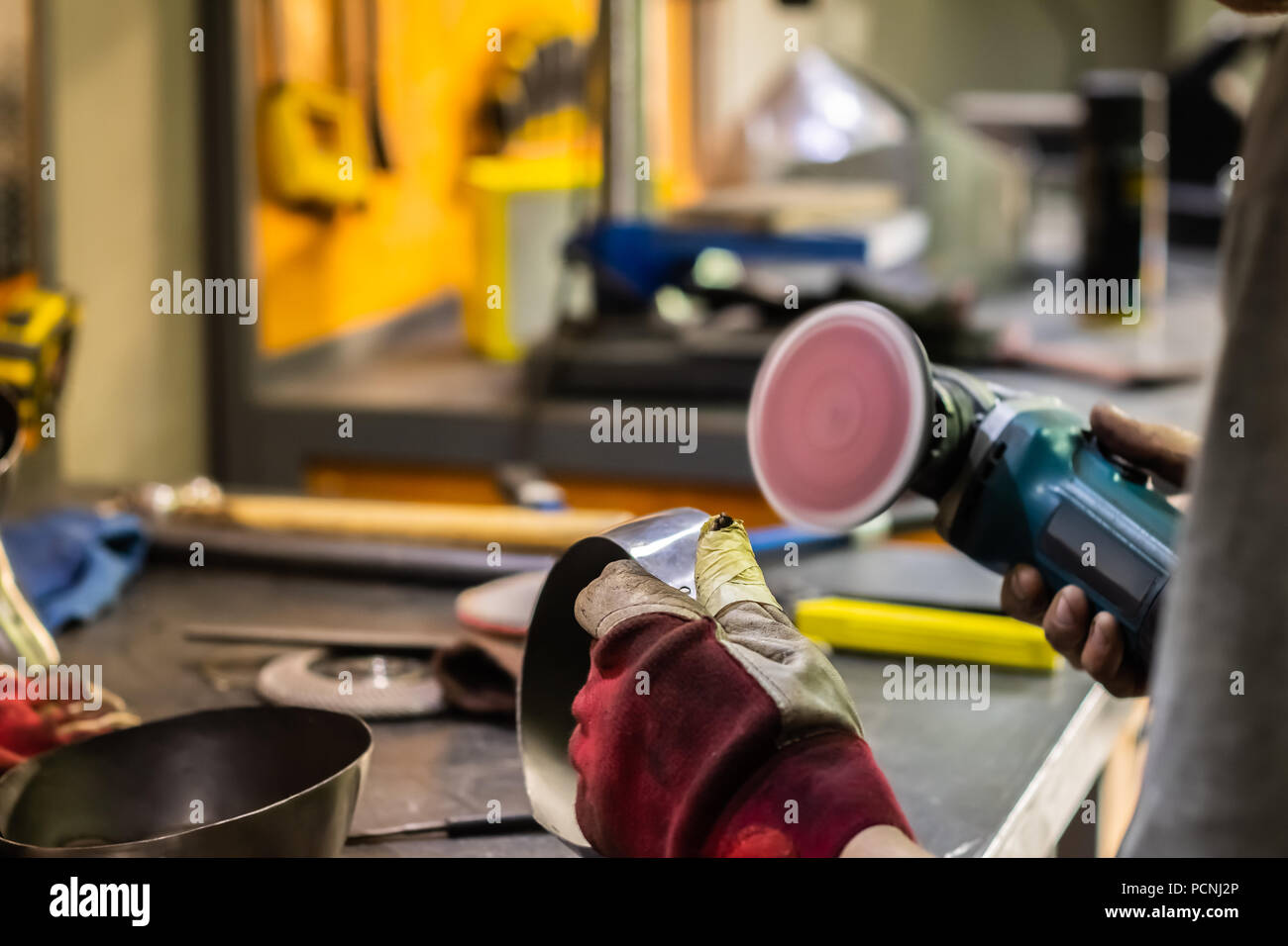 Man Hände Behandeln von Metallen Teile der Hardware in einem Workshop mit Winkelschleifer. Männliche Metallarbeiter, Polieren und Abschluss Stück der mittelalterlichen Rüstung. Stockfoto