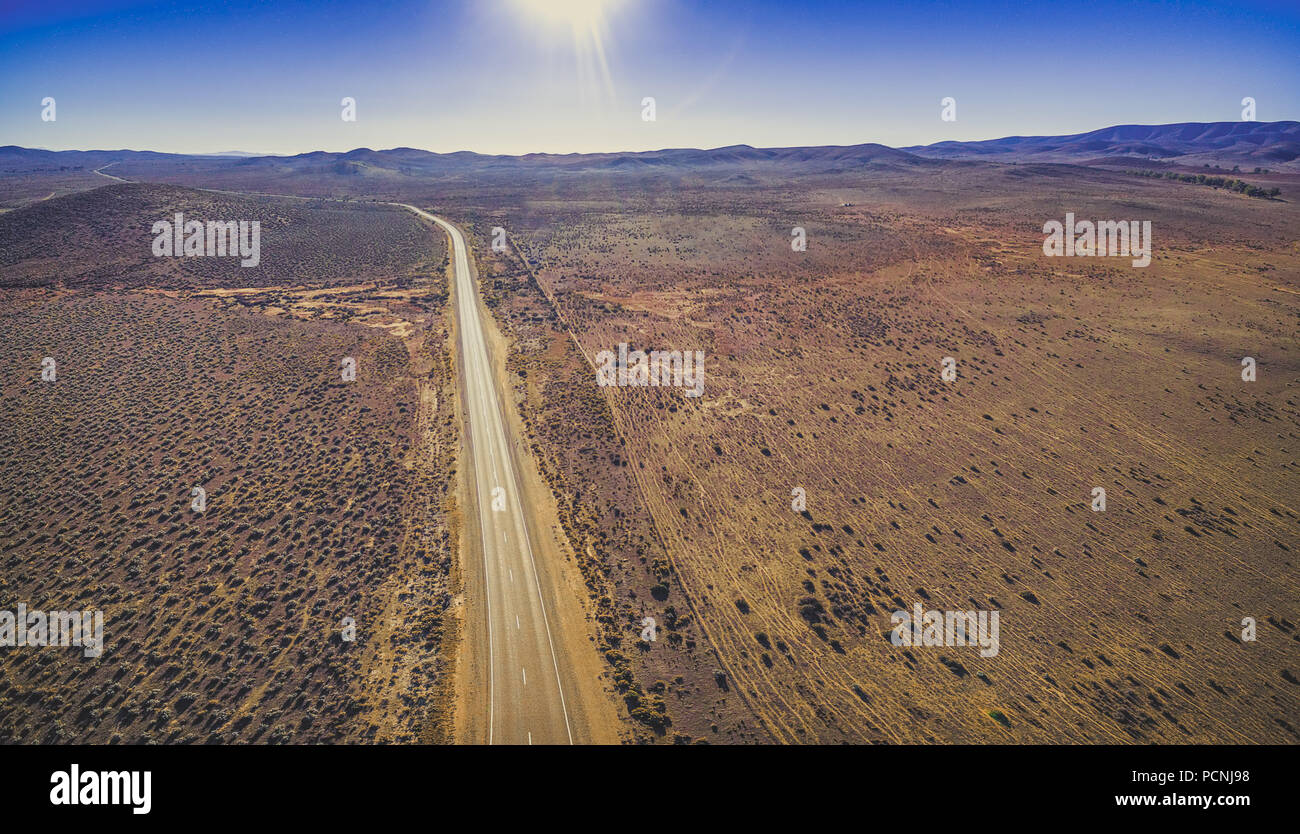 Ländliche Straße durch trockenes Land mit knappen Vegetation auf sonnigen Tag - Luftbild panorama Stockfoto