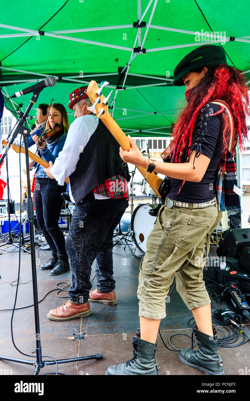 Seitenansicht, französische Folk Rock Band Triskelles auf der Freilichtbühne. Gitarrist Reden Rock am Nächsten, dann Fred rok an der Gitarre, und Fiddle Player. Stockfoto