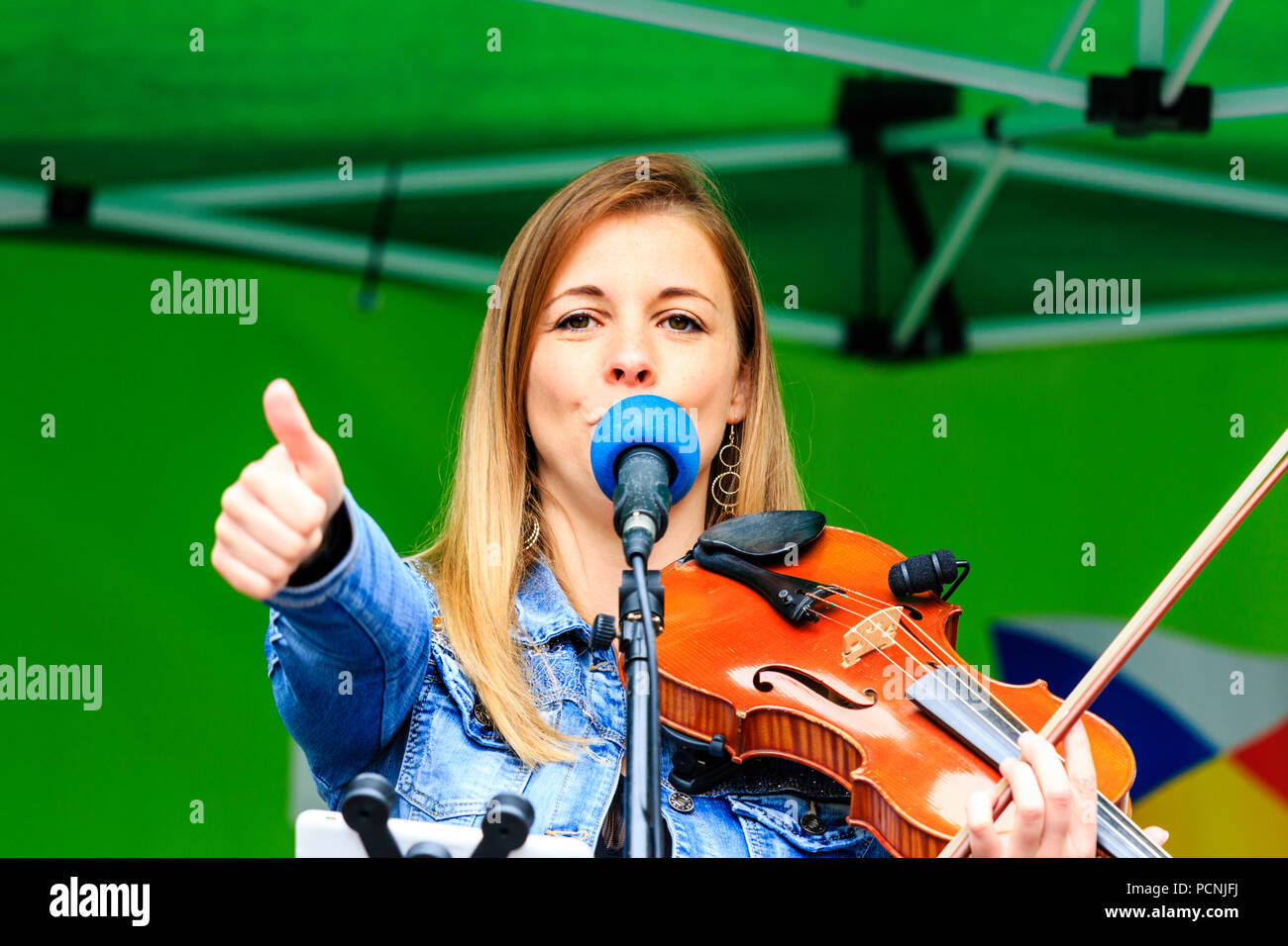 Kaukasische Frau, 20 Jahre, spielte Geige und Gesang bei Open-air-Konzert. Französische folk rock Band Triskelles Durchführen einer open-air-Konzert. Daumen nach oben Geste. Stockfoto