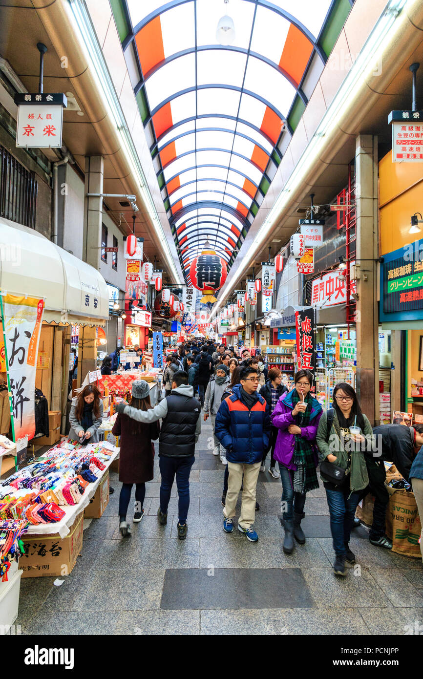 : Kuromon Ichiba, Küche essen Osaka's Markt. Blick entlang Arcade mit Ständen und Geschäften auf beiden Seiten. Besetzt mit Menschen überfüllt. Winter. Hohe Betrachtungswinkel Stockfoto