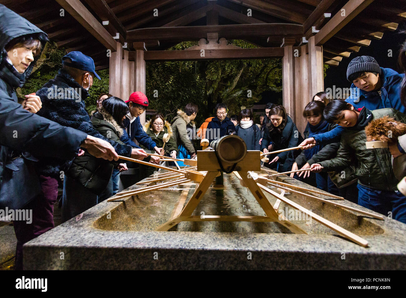 Shogatsu, Neues Jahr, Nishinomiya Shinto Schrein, Japan. Reinigung von Waschbecken, chozuya, um Mitternacht mit Menschen ankommen für Hatsumode, erster Besuch verpackt. Stockfoto