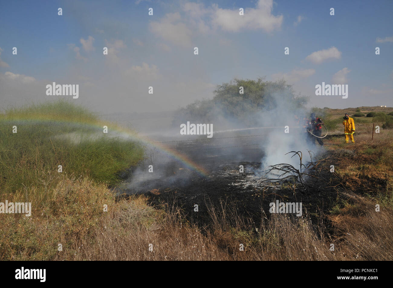 Feuerwehrmänner, die Bekämpfung eines Brandes, der von palästinensischen Kite Bomben, die von Gaza mit einer beleuchteten Benzin getränkte Lappen geflogen wurden, um Brände zu israelischen Felder ein Stockfoto