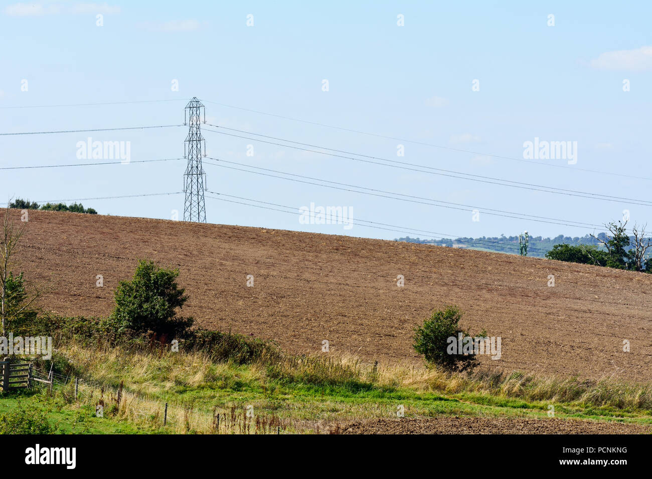 Britische countrysode Szene mit gepflügten Feldes und Strom Pylon - mit traditionellen und modernen Lebensstil Stockfoto