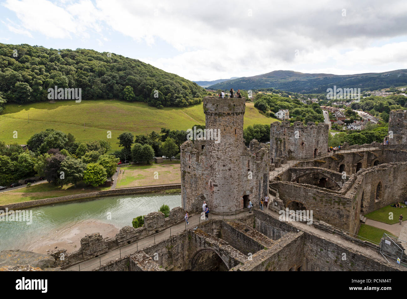 Ein Blick auf einige der Gebäude, die Conwy Castle im Norden von Wales, die umliegenden Hügel und Berge im Hintergrund. Stockfoto